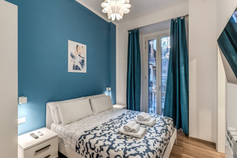 Letto matrimoniale con copriletto fantasia e comodini – affitto breve a Roma zona centrale