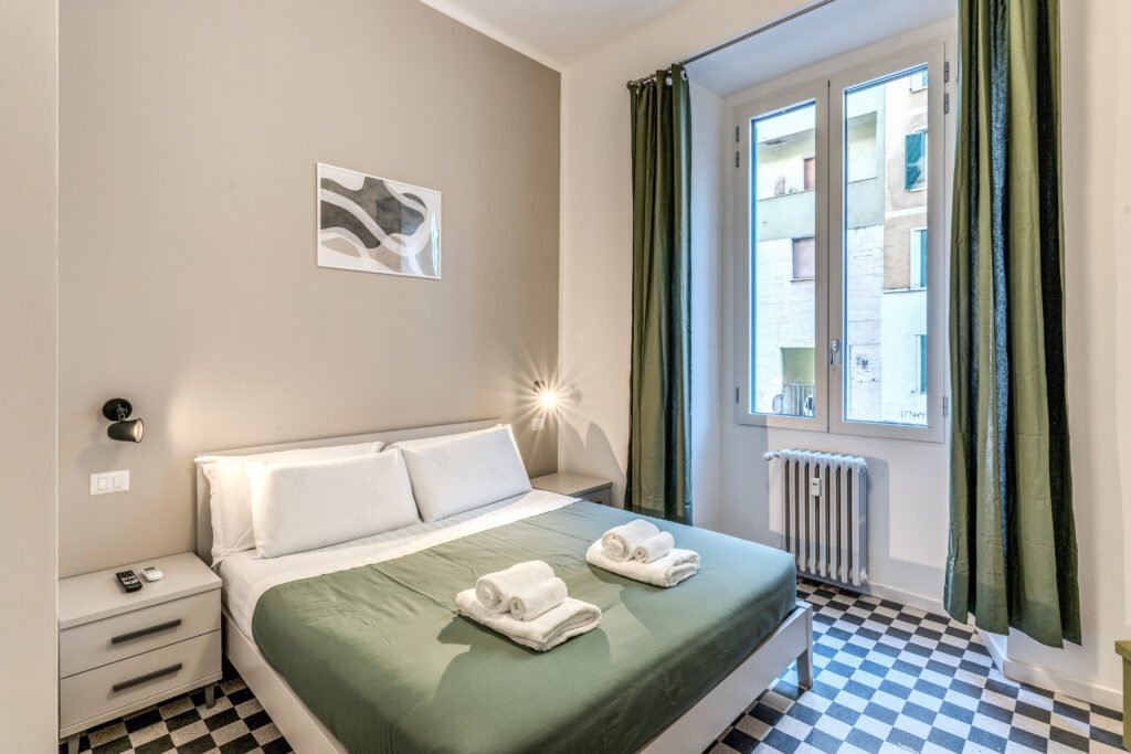 Camera matrimoniale con lenzuola piegate e luce naturale – affitto breve a Roma centro
