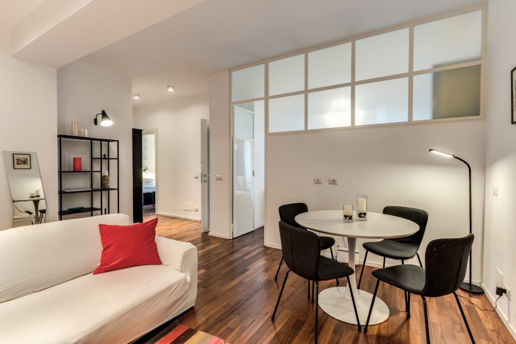 Soggiorno moderno con divano bianco, area pranzo e pavimenti in legno - case vacanze roma centro