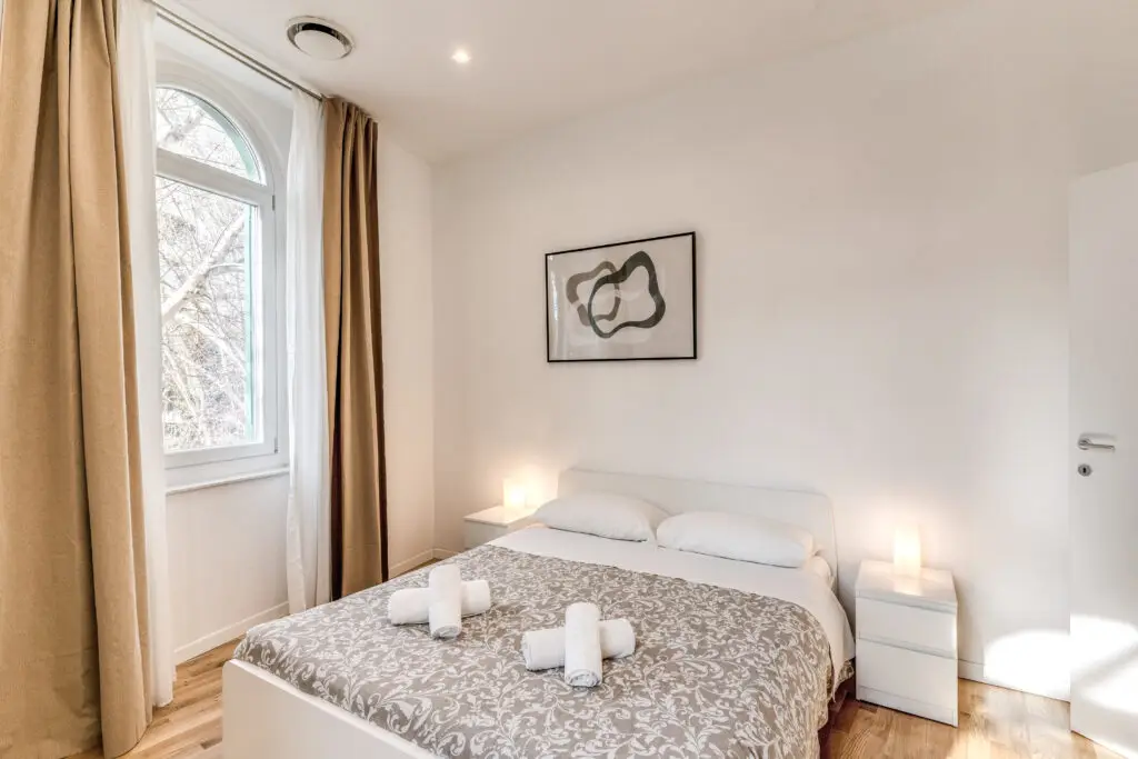 Letto matrimoniale con lenzuola fresche e luce naturale – soggiorno a Roma
