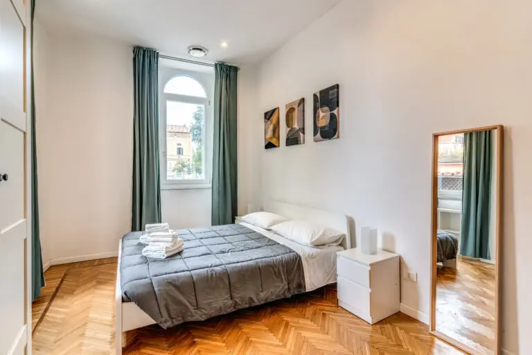 Camera ampia con parquet, comodini e decorazioni alle pareti – alloggio Domus Dianae